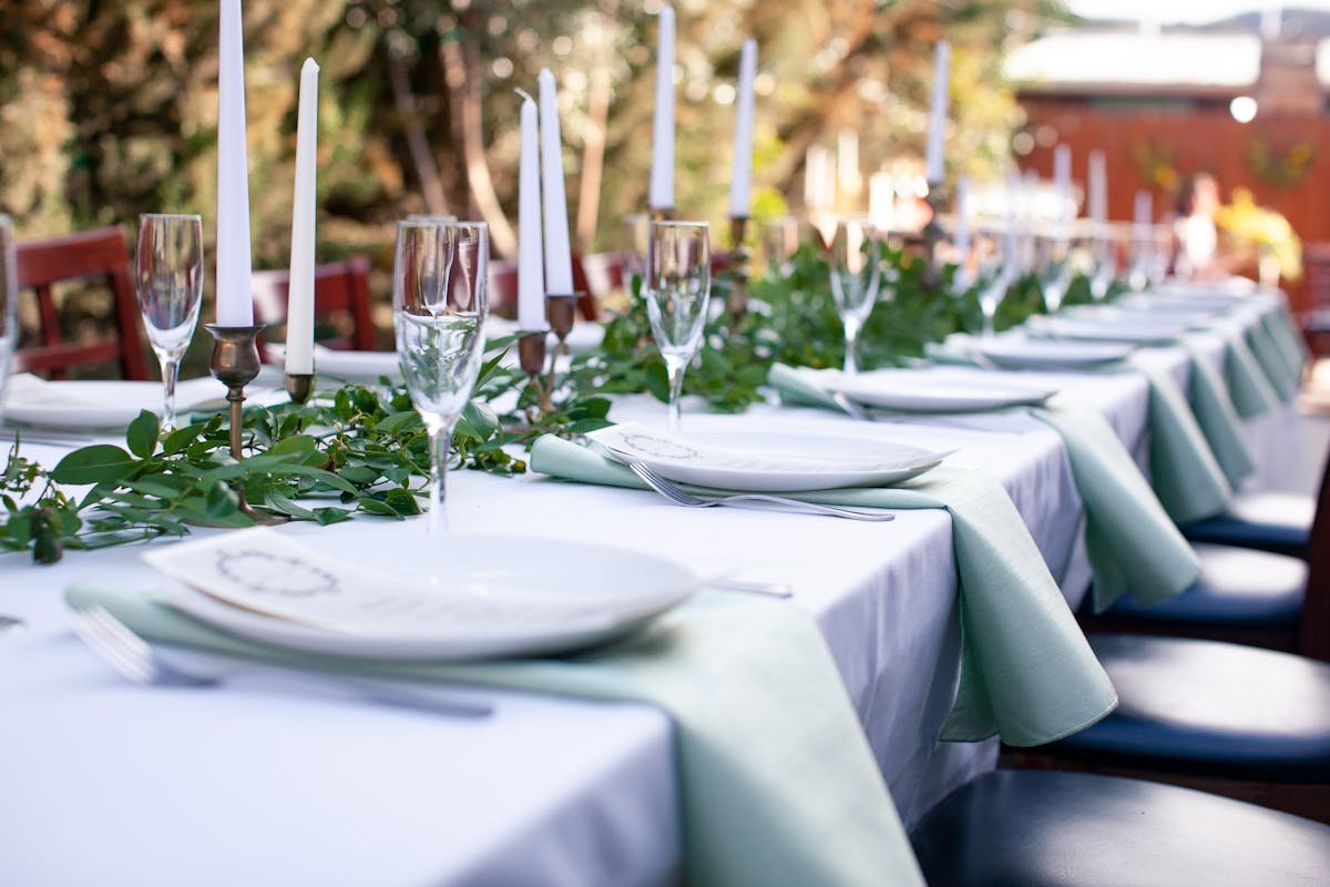 Candlelit place settings running down a long courtyard table at dusk